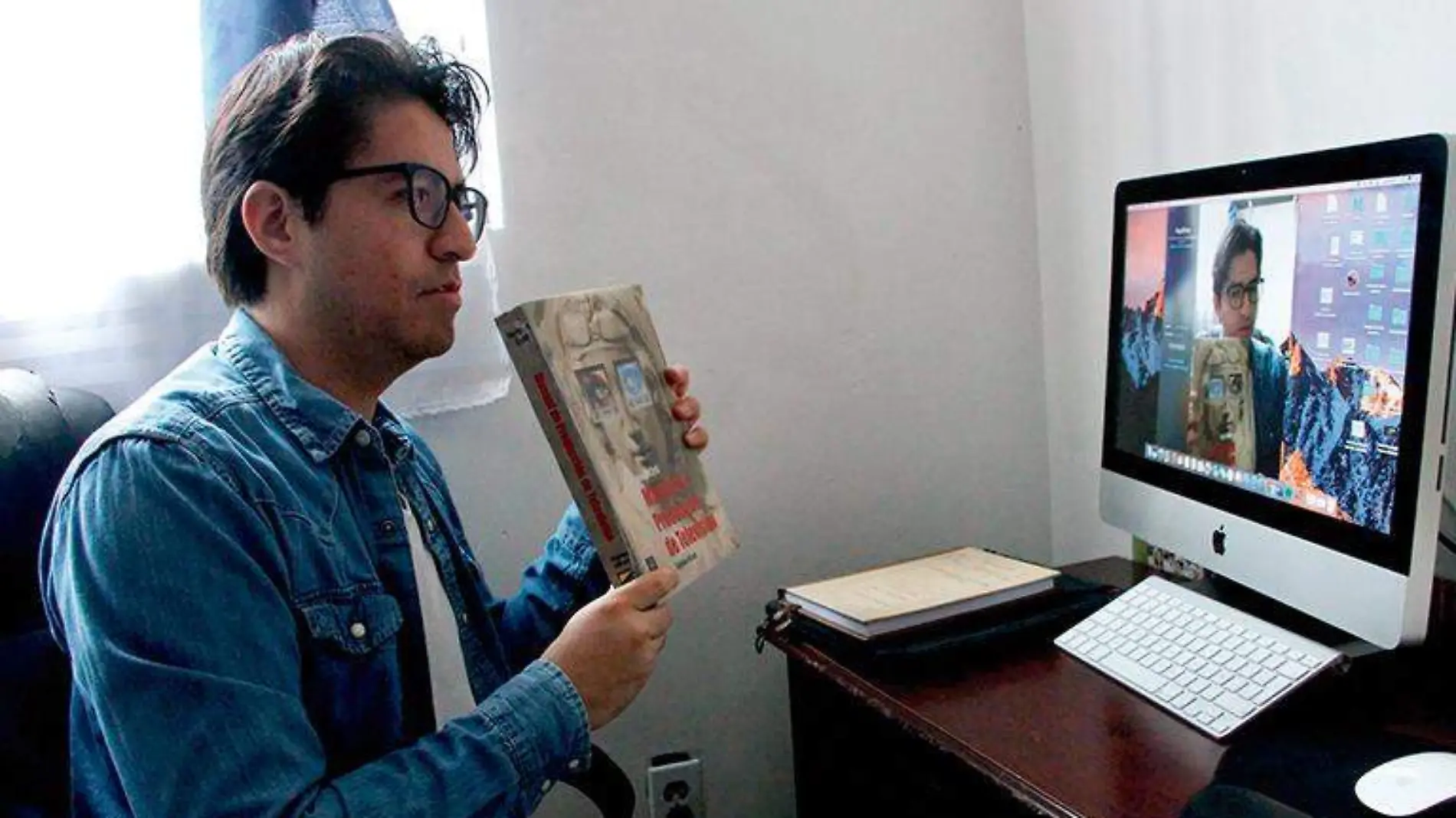 Profesor muestra un libro durante una clase a distancia